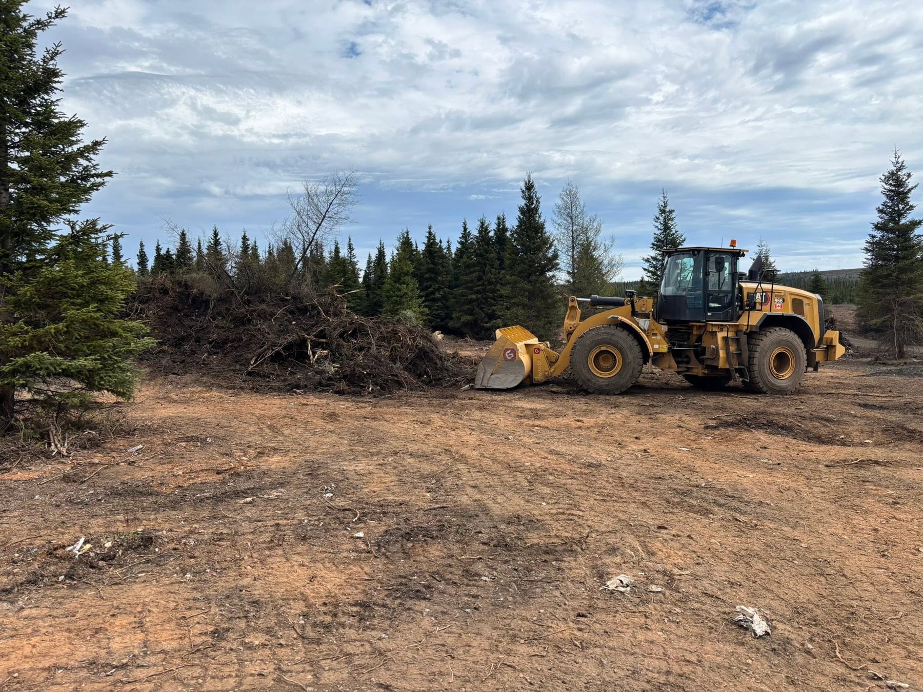 Loader beside a pile of branches during land clearing.