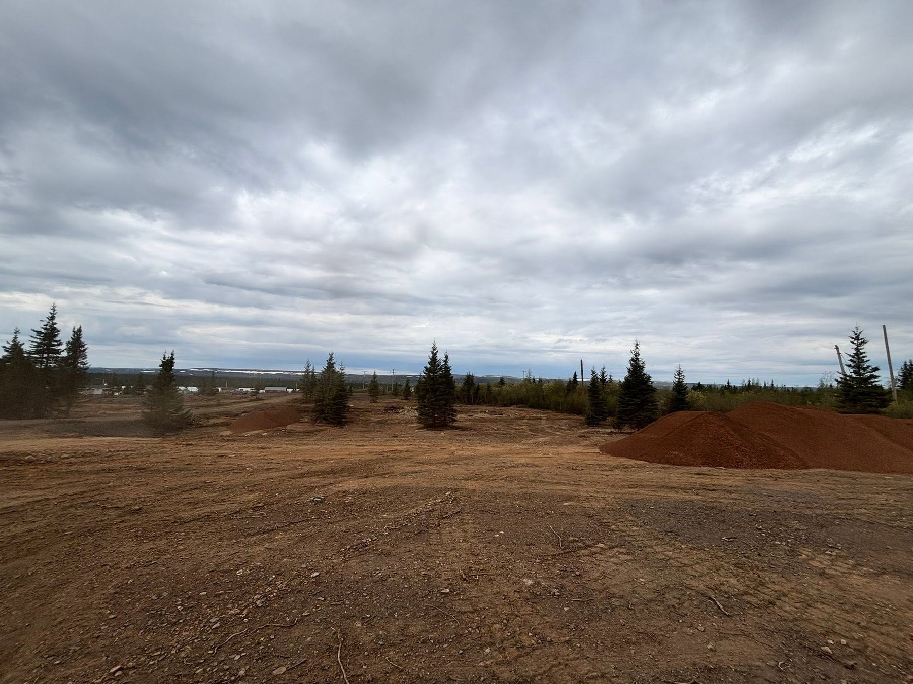 Soil piles and cleared land for site setup.