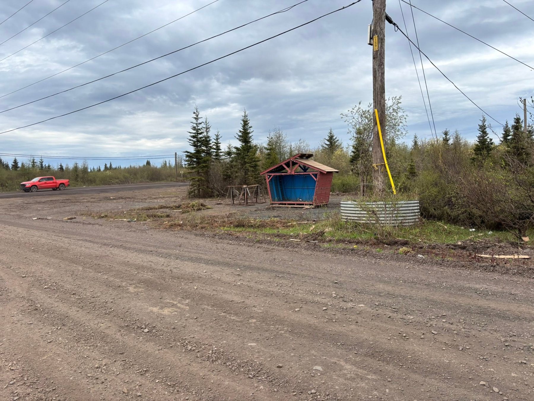 Small red shelter near the road and cleared area.
