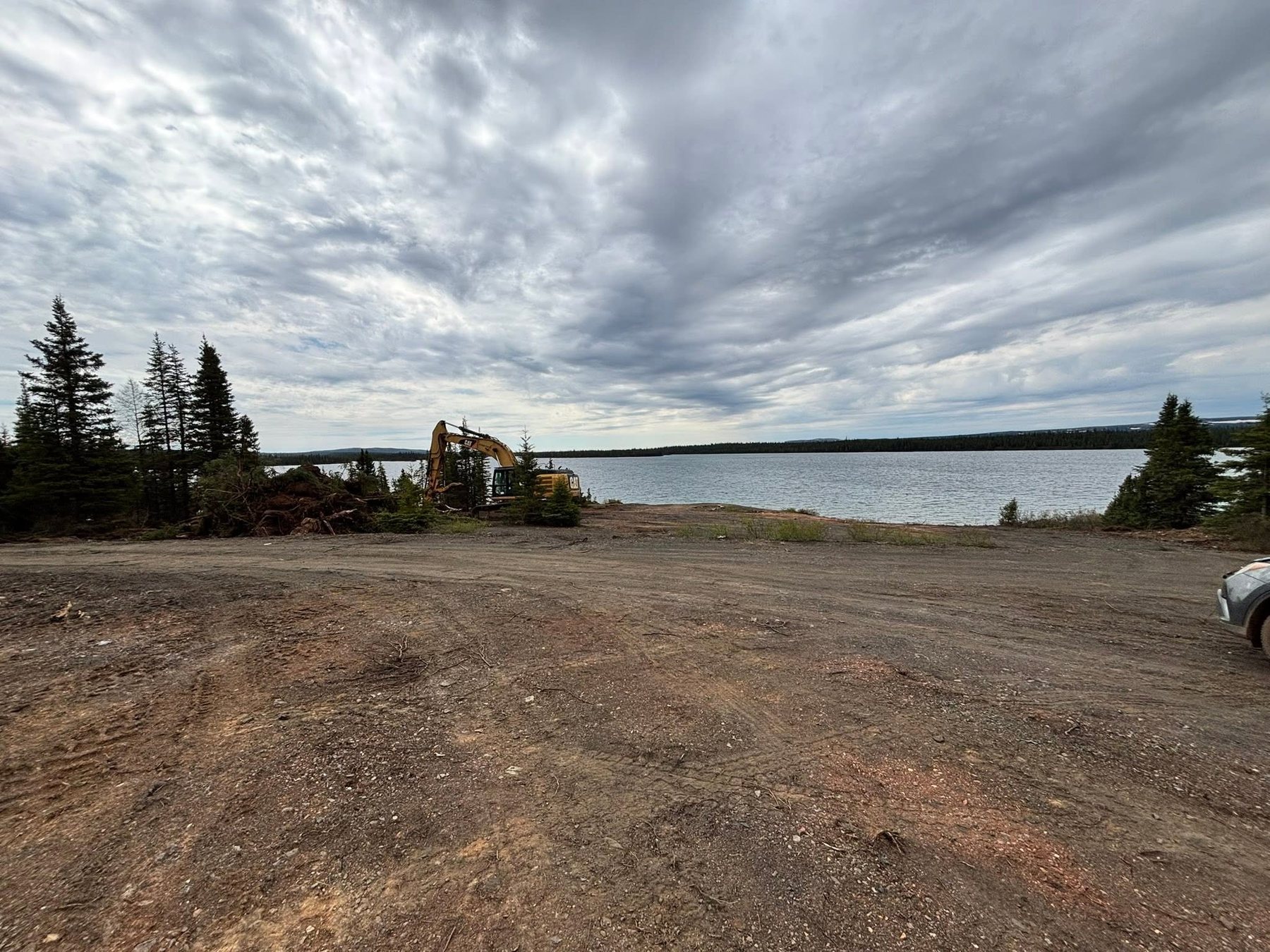 Excavator near the lake during preparation work.
